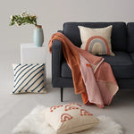 Un espace de vie accueillant avec un canapé sombre, des coussins décoratifs colorés et une décoration florale apportant une touche de chaleur et de confort.