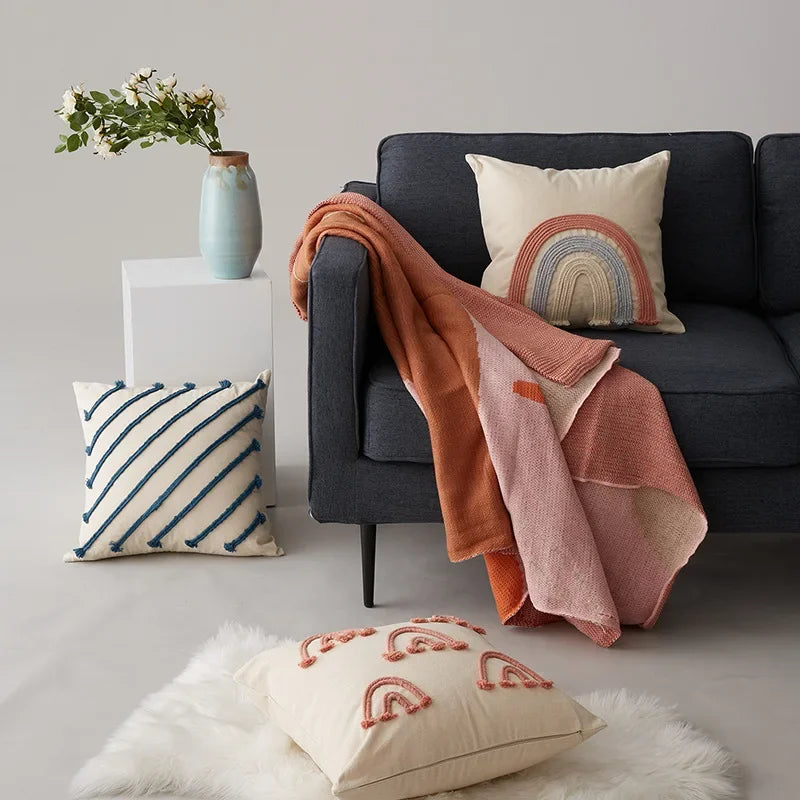 Un espace de vie accueillant avec un canapé sombre, des coussins décoratifs colorés et une décoration florale apportant une touche de chaleur et de confort.