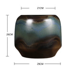 Un élégant vase de style moderne avec des nuances de vert, de brun et de bleu, aux formes arrondies et lisse.