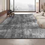Un tapis gris moderne et élégant dans un intérieur épuré, avec de grandes fenêtres offrant une vue sur un paysage enneigé.