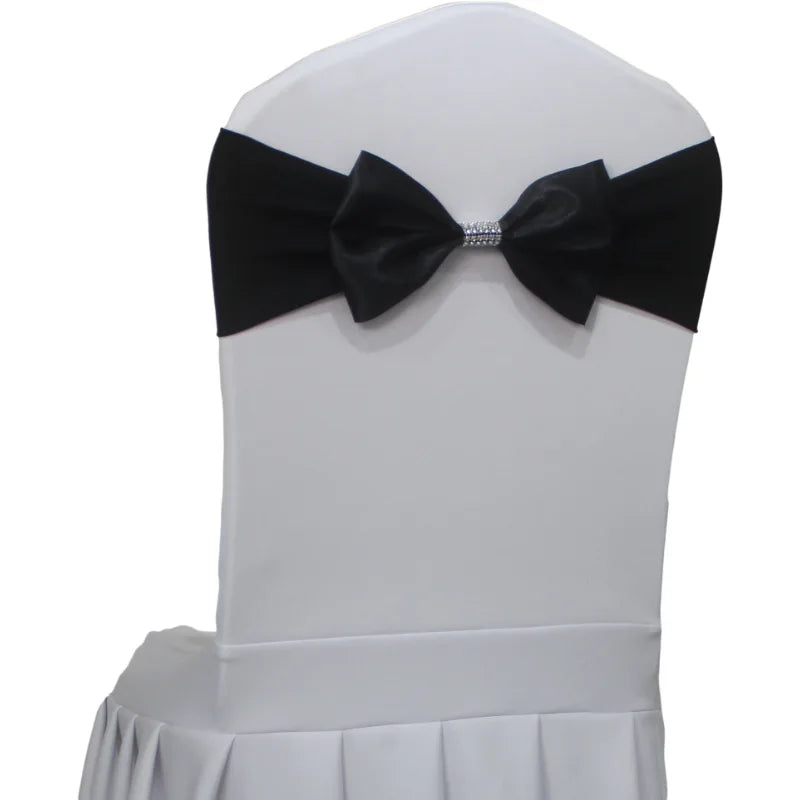 Une chaise recouverte d'un tissu blanc avec un nœud papillon noir et un détail brillant à la taille.