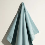 Une serviette élégante et raffinée en nuances de bleu pâle, aux plis harmonieux et à l'apparence soignée.