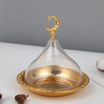 Une élégante cloche en verre doré ornée d'une lune et d'une étoile scintillante, posée sur un plateau décoratif, évoquant une atmosphère sereine et sophistiquée.