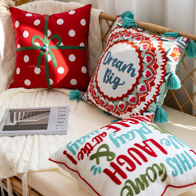 Un ensemble de coussins décoratifs colorés et amusants, avec des motifs à pois rouges et blancs ainsi que des motifs graphiques vivaces, créant une ambiance ludique et chaleureuse dans la pièce.