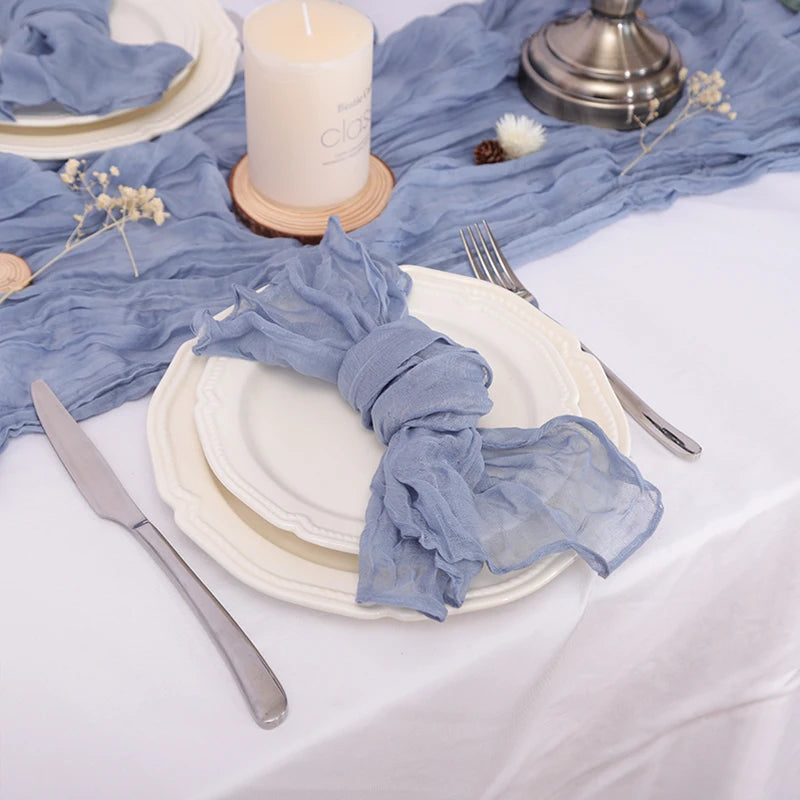 Un arrangement de table élégant avec des assiettes blanches, des couverts, une bougie blanche et un tissu bleu matelassé.