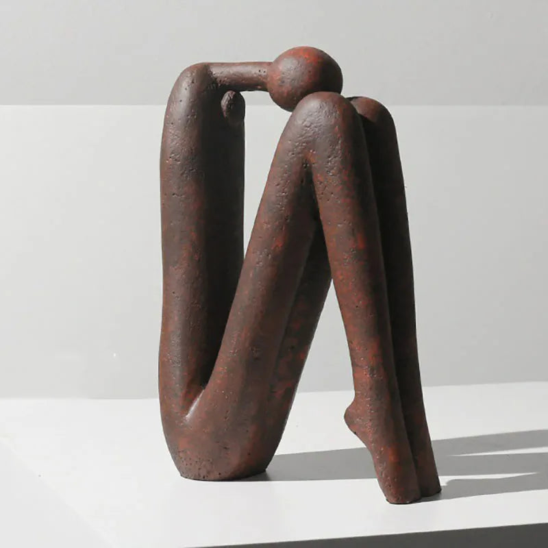 sculpture abstraite minimaliste résine brune blanche texture rugueuse personne assise décoration intérieure étagère salon