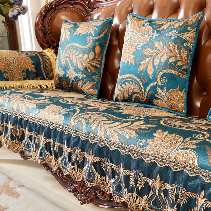 Coussin en velours bleu avec des motifs dorés floraux et ornementaux, posé sur un canapé en bois de couleur foncée.