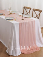 Une table dressée élégamment avec une nappe rose pâle, des assiettes, des verres et des bougeoirs dorés, créant une ambiance chaleureuse et raffinée.