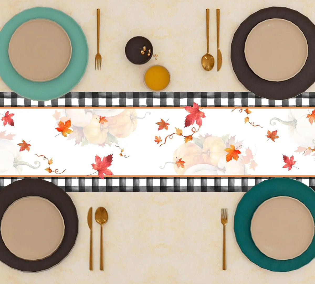 Une table de repas automnale avec des assiettes et des couverts dorés, soulignée par une décoration de feuilles d'érable rougeoyantes.