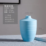 Vase en céramique turquoise avec un motif de rayures verticales, mesurant 12,7 cm de hauteur et 1,7 cm de diamètre.