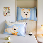 Un ours polaire mignon imprimé sur un oreiller bleu et blanc, créant une ambiance cozy et ludique dans la chambre.