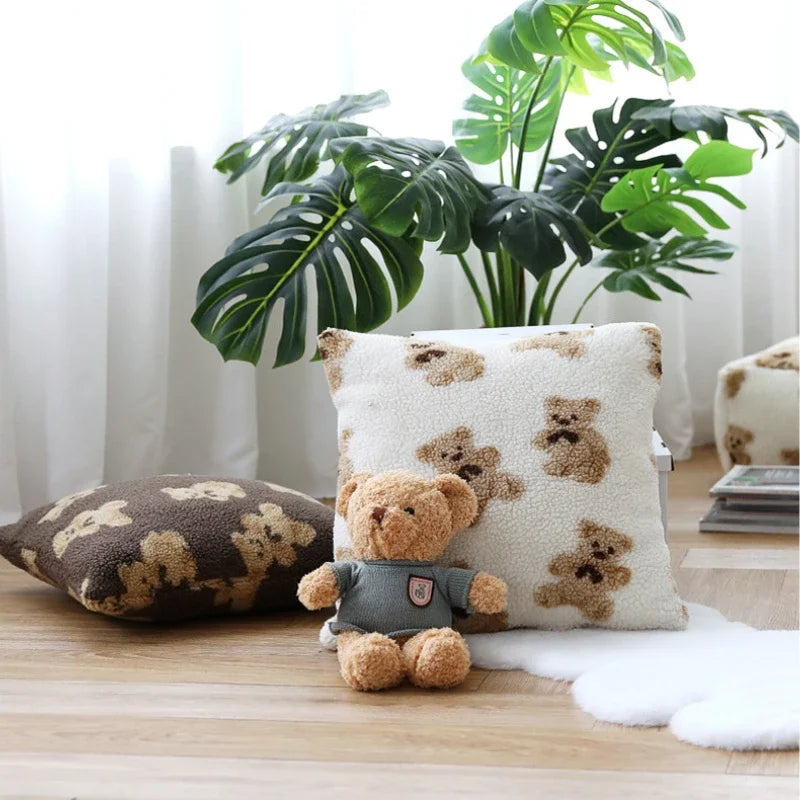 Coussin décoratif moelleux avec un motif de nounours, entouré de plantes vertes luxuriantes, créant une ambiance cosy et chaleureuse dans la pièce.