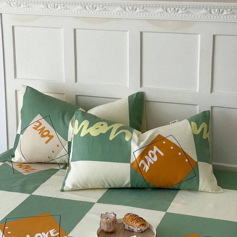 Des coussins carrés décoratifs de couleurs vert et orange avec des motifs géométriques, posés sur un sol carrelé et blanc, avec des pâtisseries sur une table.
