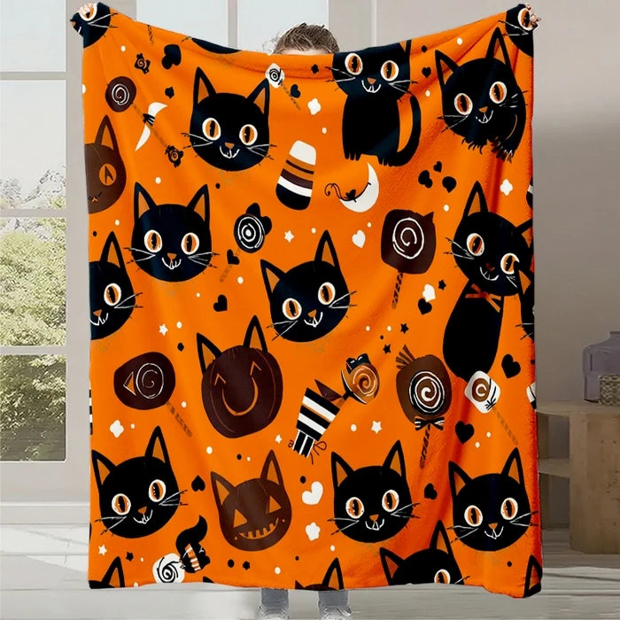Couverture orange avec des motifs de têtes de chats noirs sur un fond orange vif, parfaite pour une ambiance Halloween festive.