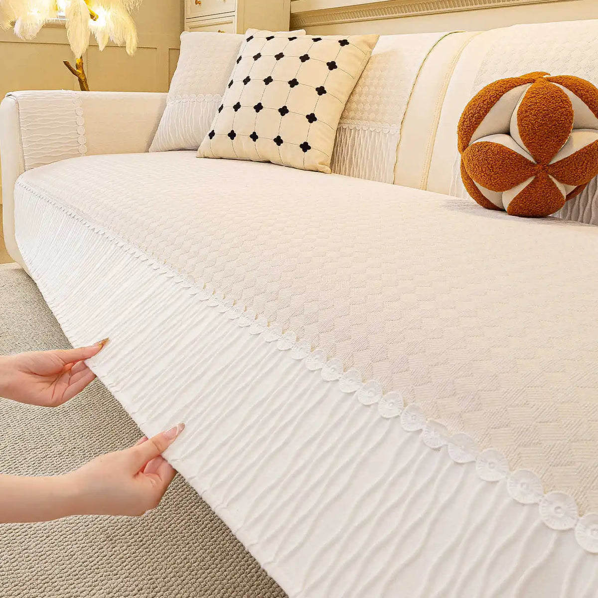 Un canapé cosy et douillet, avec des coussins blancs à motifs géométriques noirs et une jolie boule décorative orange, créant une atmosphère chaleureuse et accueillante dans la pièce.