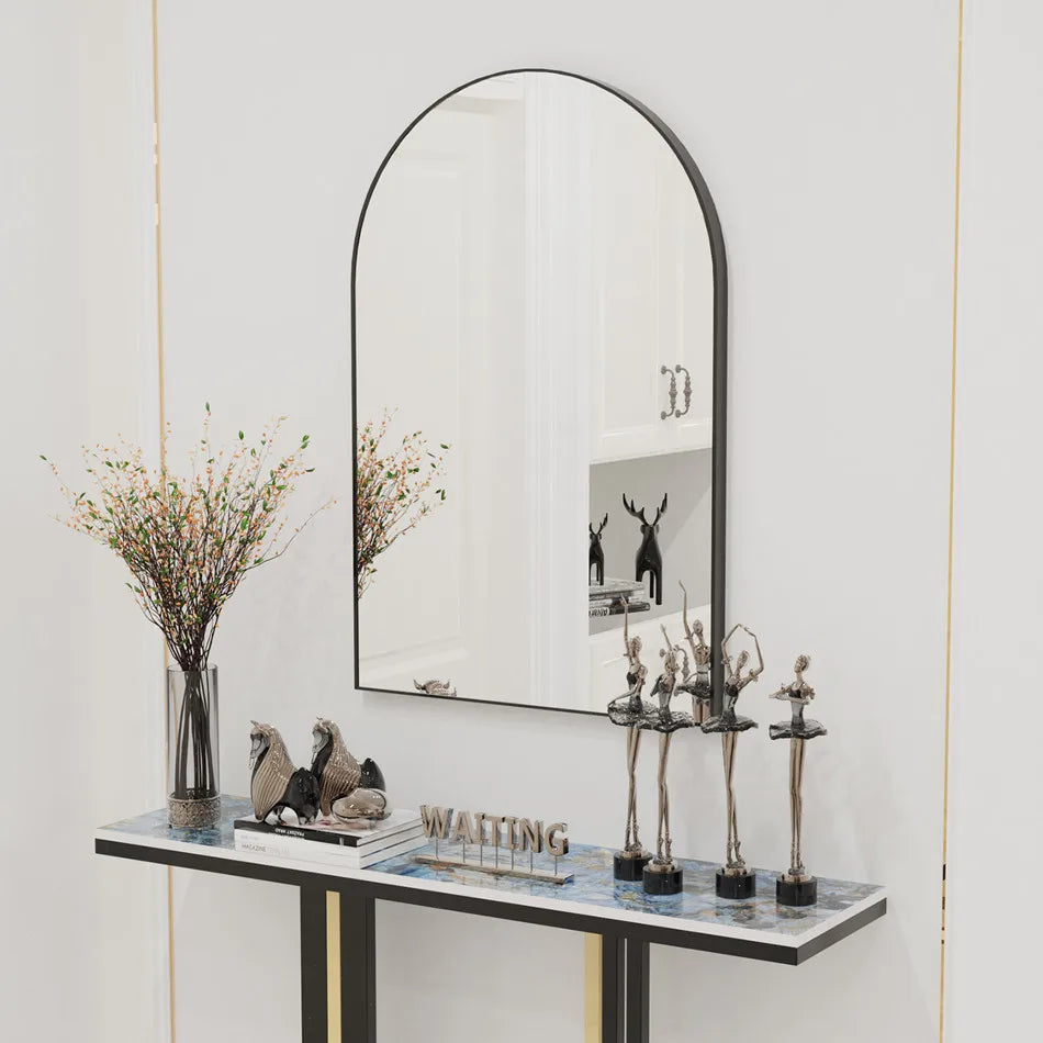 Miroir élégant sur une console décorée de figurines et d'un bouquet de fleurs, créant une atmosphère chaleureuse et de bon goût dans cette pièce blanche.