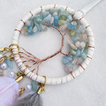 Un captivant collier en perles et pierres semi-précieuses, entouré d'une structure en fil de cuivre formant un motif circulaire élégant.