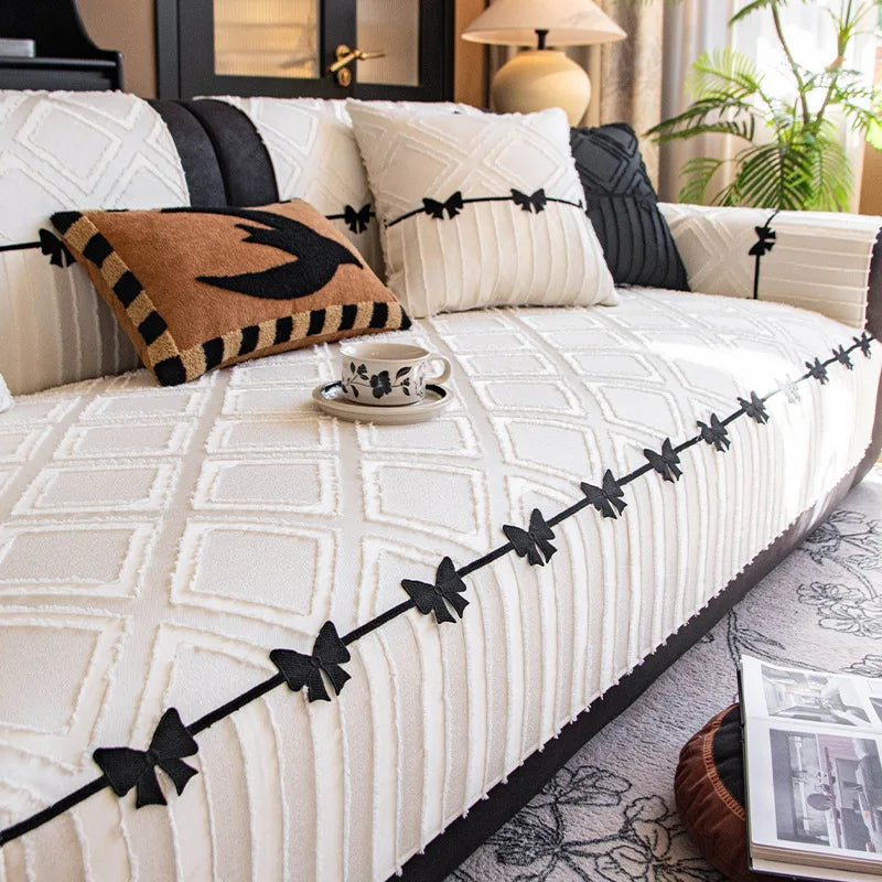 Cette chambre confortable et élégante présente un lit avec une couverture blanche ornée de motifs graphiques noirs, des oreillers décoratifs et des accessoires de style rétro qui créent une atmosphère chaleureuse et raffinée.