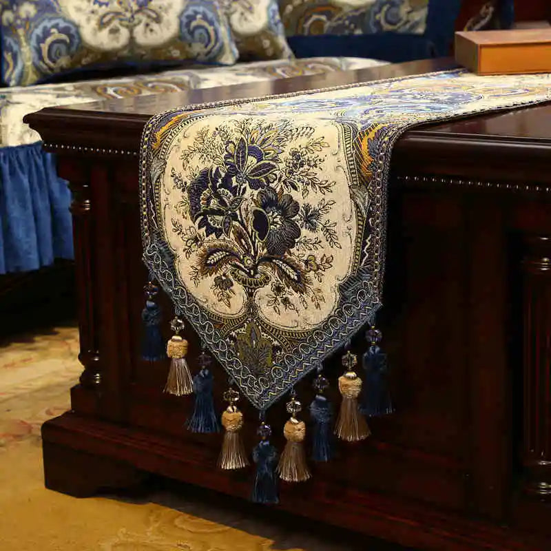 Tapis de table en tissus ornementés de motifs floraux avec des pompons et des glands décoratifs.