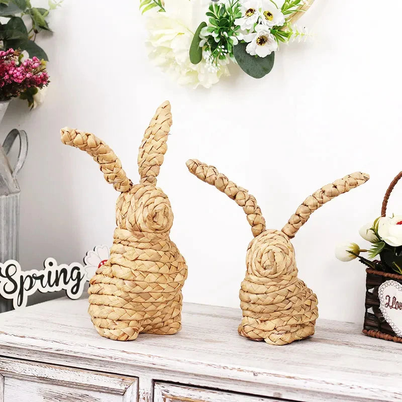 Deux figurines de lapins en osier tressé posées sur un meuble décoré de fleurs et de panneaux indiquant le printemps.