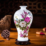 Vase en porcelaine blanche décoré de fleurs colorées épanouies, d'oiseaux et de branches fleuries, sur un support en bois foncé.