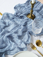 L'image montre un joli set de table avec un tissu bleu soyeux, des ustensiles dorés et un verre en cristal, créant une atmosphère élégante et raffinée.