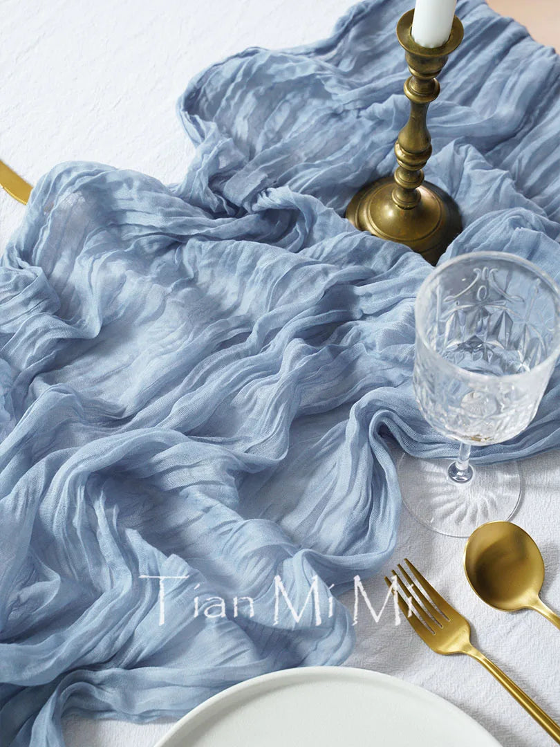 L'image montre un joli set de table avec un tissu bleu soyeux, des ustensiles dorés et un verre en cristal, créant une atmosphère élégante et raffinée.