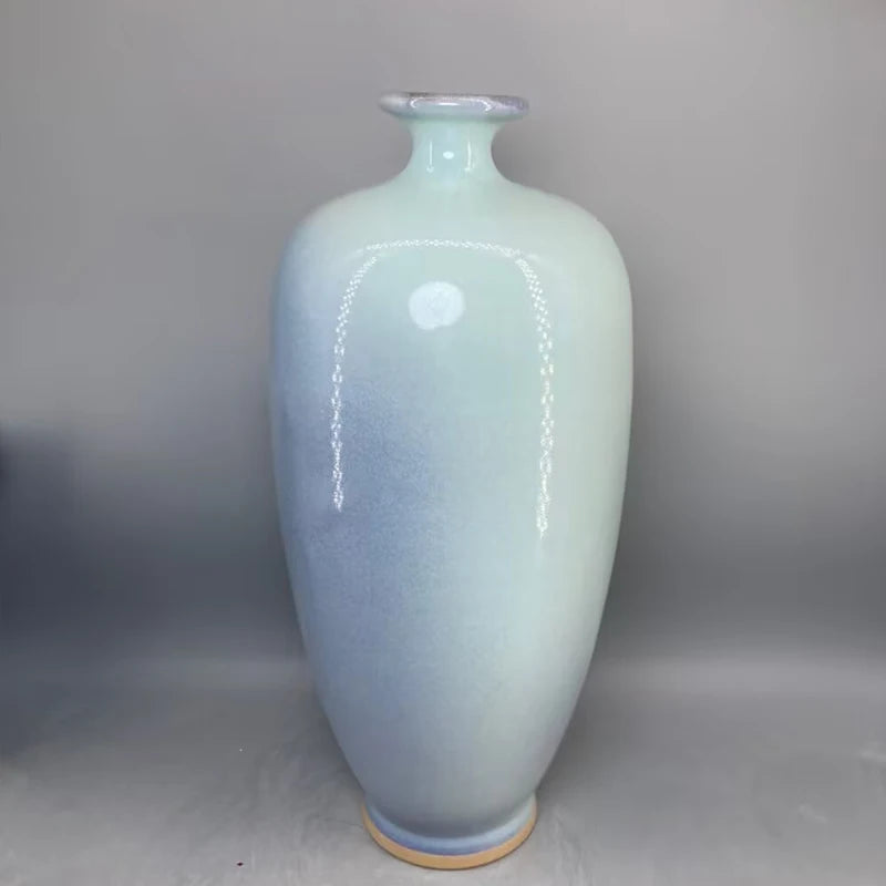 Un vase en céramique de couleur vert pâle avec une finition brillante et un motif décoratif.
