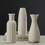Trois vases en céramique blanche aux formes épurées et élégantes, disposés sur un fond sombre, créant une atmosphère sophistiquée.