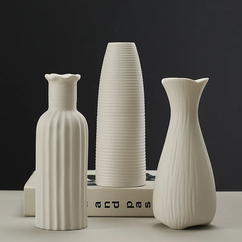 Trois vases en céramique blanche aux formes épurées et élégantes, disposés sur un fond sombre, créant une atmosphère sophistiquée.