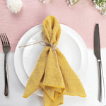 Une élégante serviette jaune nouée sur une assiette blanche, avec des couverts argentés, sur un fond rose doux.