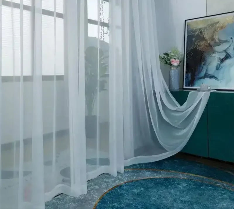 Rideau en voile blanc fluide tombant au sol dans une pièce moderne avec déco artistique