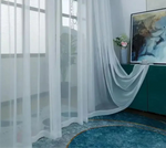 Rideau en voile blanc fluide tombant au sol dans une pièce moderne avec déco artistique