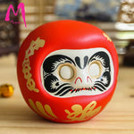 statuette japonaise daruma rouge blanche visage sourire yeux grands ouverts motifs dorés traditionnels décoration