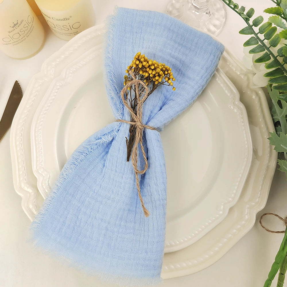 Détail de la table de dîner avec une serviette en lin bleu et un bouquet de fleurs jaunes attaché avec de la ficelle.