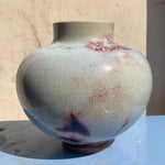 Un vase céramique aux tonalités bleutées et rougeâtres, avec une texture craquelée lui conférant un aspect unique et vintage.