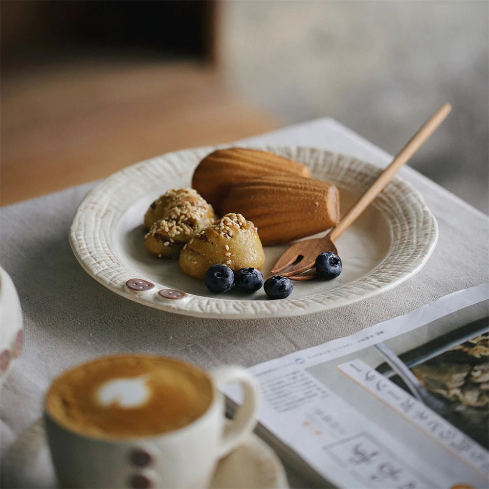 Un plateau de desserts et une tasse de café, avec des muffins, des baies et une décoration en bois, sur un fond flou.