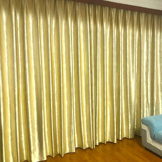 Vue d'ensemble d'une grande baie vitrée habillée de rideaux dorés fermés, créant un effet luxueux et élégant dans une pièce chaleureuse.
