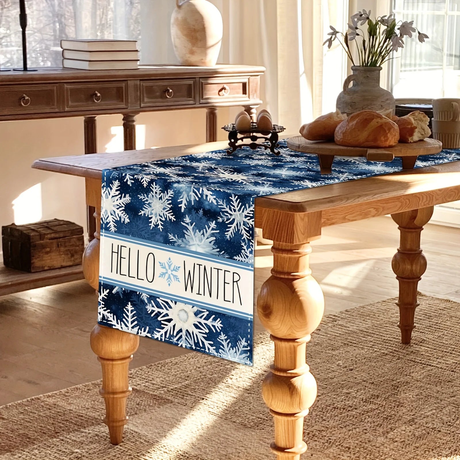 Une belle table en bois avec un chemin de table en motif de flocons de neige bleus et blancs, avec un message "Hello Winter" accentuant l'ambiance hivernale.