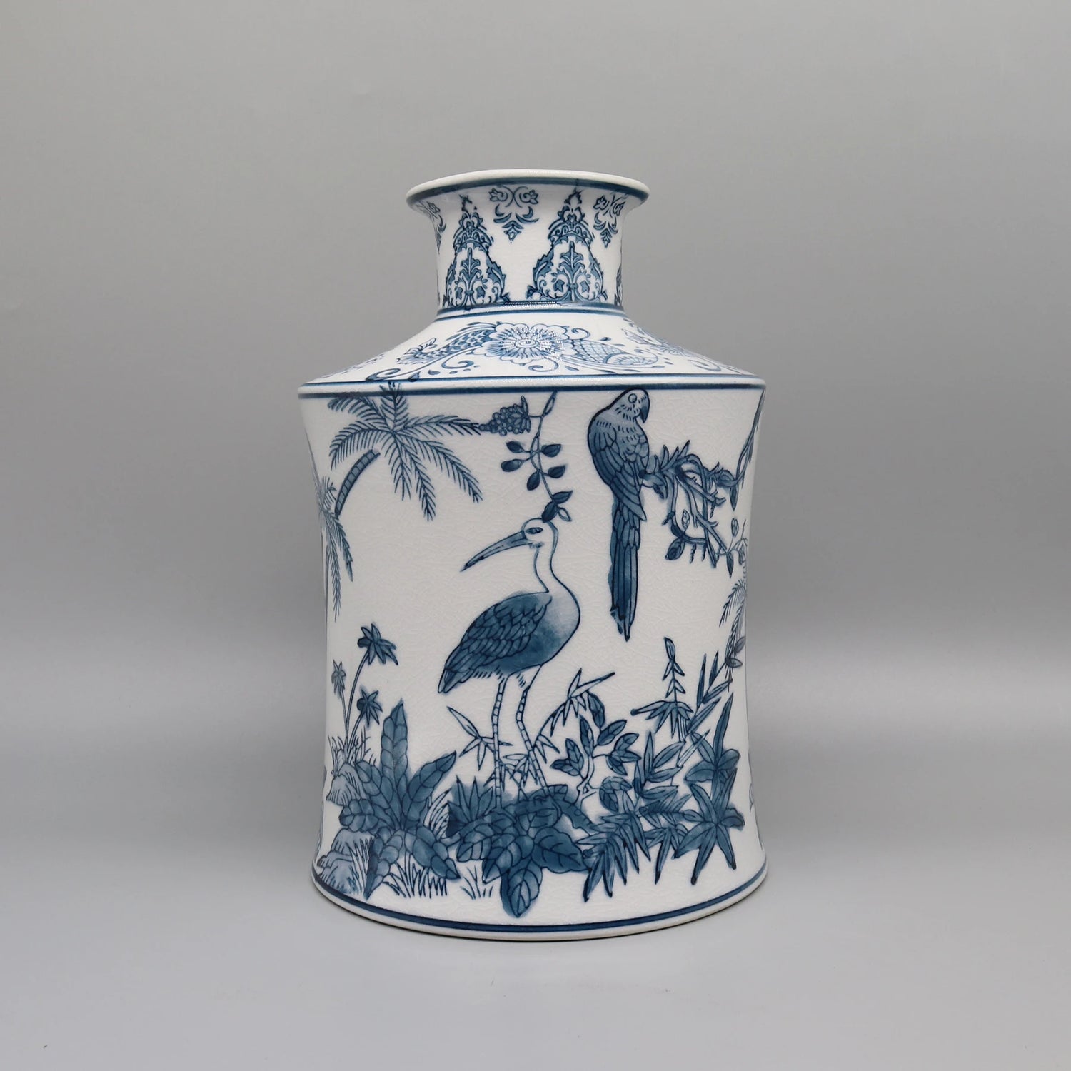Joli pot de porcelaine bleu et blanc décoré de motifs floraux et d'oiseaux exotiques, créant une scène de jardin tropical.
