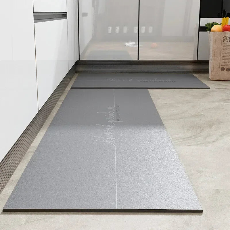 Tapis d'entrée en caoutchouc gris avec inscription argentée, placé dans un espace moderne et lumineux.