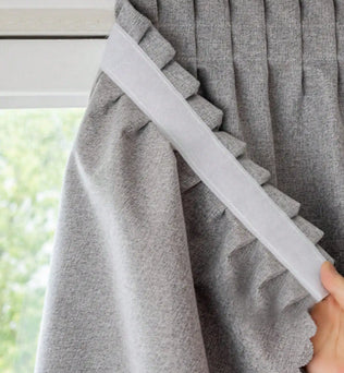 Rideau gris élégant avec plis et garniture décorative, idéal pour embellir une fenêtre et offrir une ambiance chaleureuse et moderne à votre intérieur. Ce rideau s'adapte facilement à différents styles de décoration et est parfait pour contrôler la lumière et préserver votre intimité.