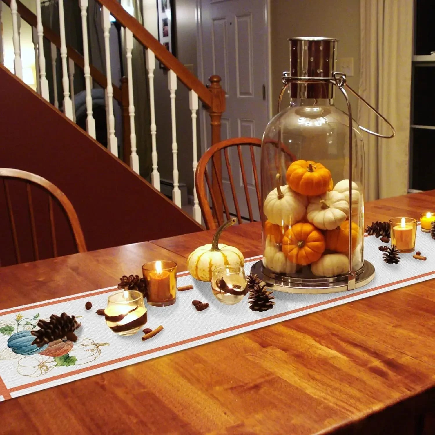 Une table décorée avec des citrouilles, des bougies et des pommes de pin pour créer une ambiance chaleureuse et automnale.