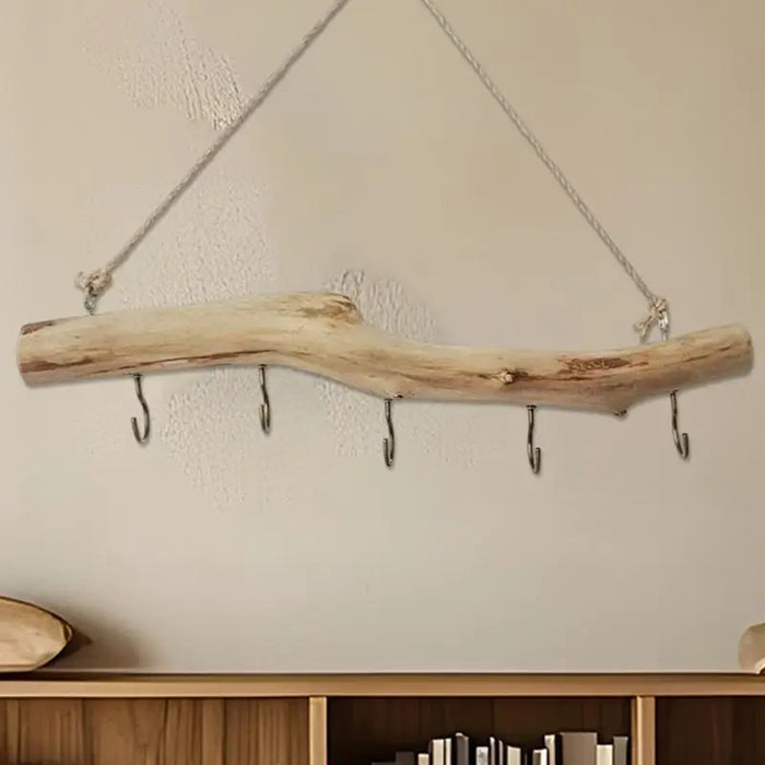 Branche suspendue en bois flotté naturel accrochée au mur avec des bijoux