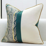 Coussin décoratif moderne avec motif géométrique noir et blanc et touches de vert, sur un canapé blanc.