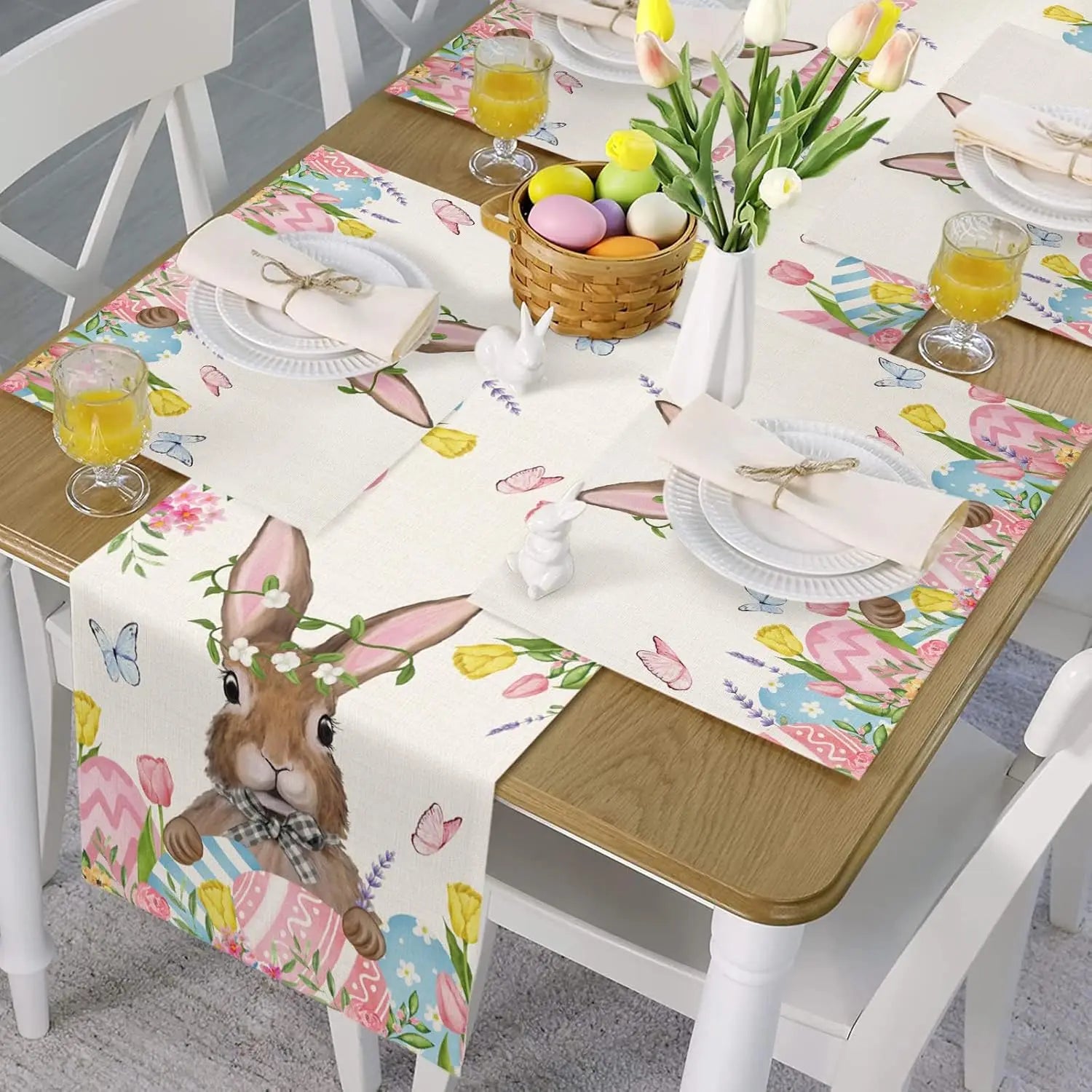 Une belle table de Pâques avec des fleurs de tulipes, un panier d'oeufs colorés, et un chemin de table décoré avec des motifs printaniers.