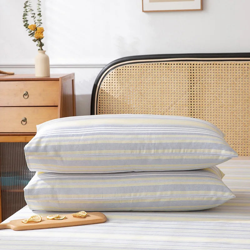 Des oreillers rayés gris et jaune posés sur un lit, dans une chambre décorée avec du mobilier en bois et des accessoires vintage.