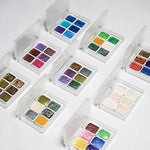 peintures aquarelle palette compacte bleu vert violet rose beige jaune blanc texture granuleuse opaques