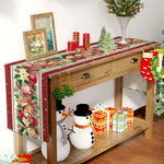 Table de Noël décorée avec un arrangement coloré de branches de sapin, de bougies rouges, de boules de Noël et d'un bonhomme de neige posé sur une étagère en bois.