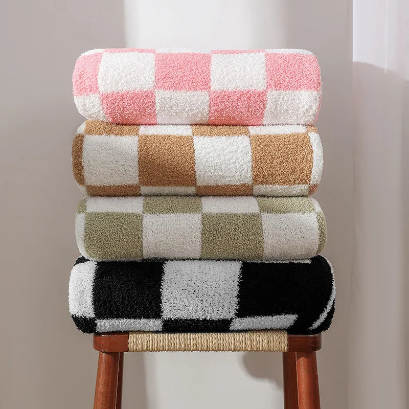 Des serviettes de bain aux motifs géométriques colorés empilées sur un tabouret en bois.